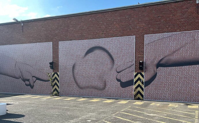 An abstract mural on a brick building with a finger pointing at a hand